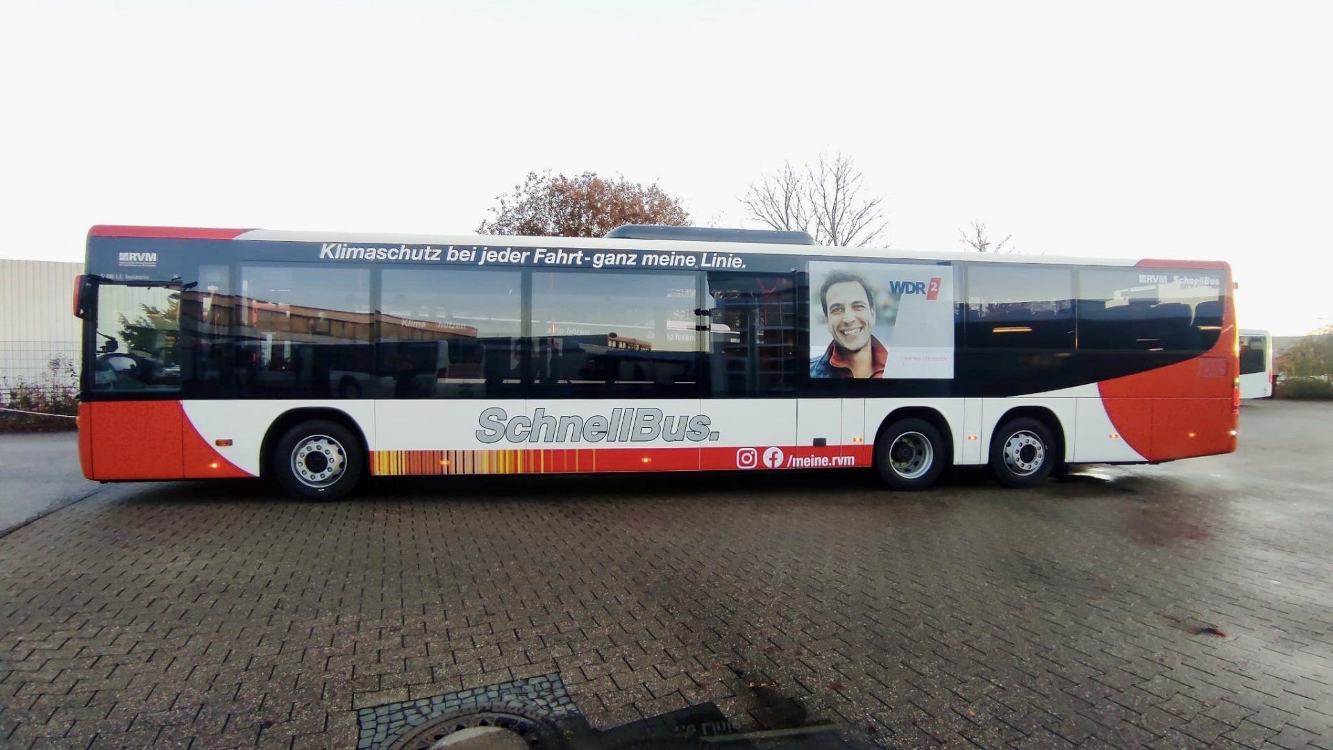 A red and white bus is parked in a parking lot.