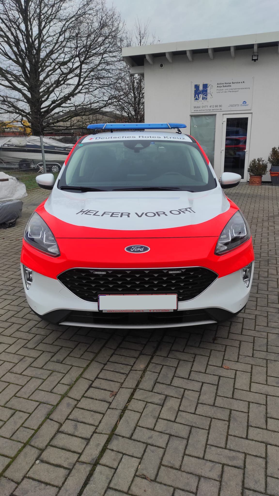 A red and white police car is parked on a brick driveway.