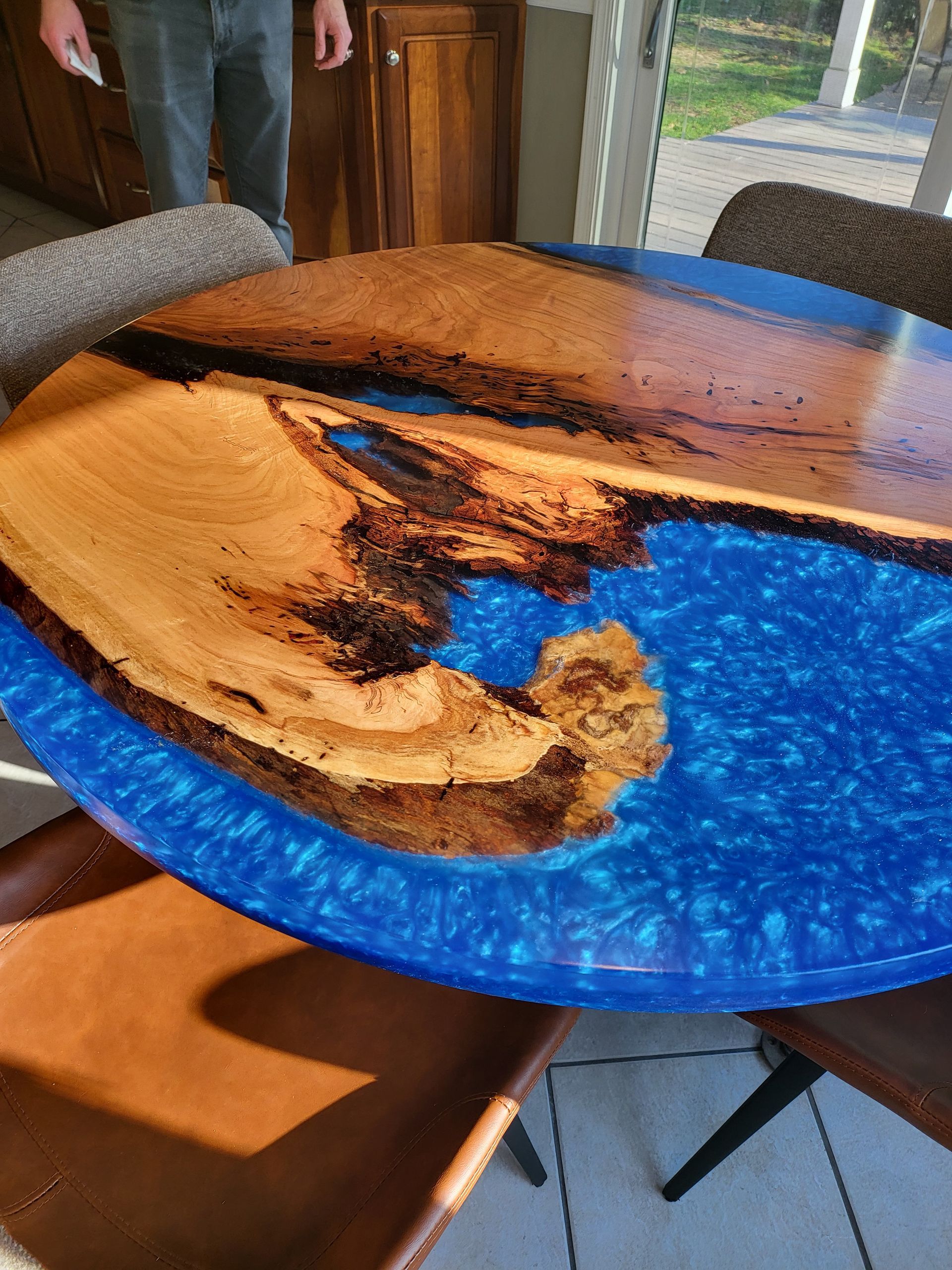 A wooden table with a blue top and a man standing behind it.