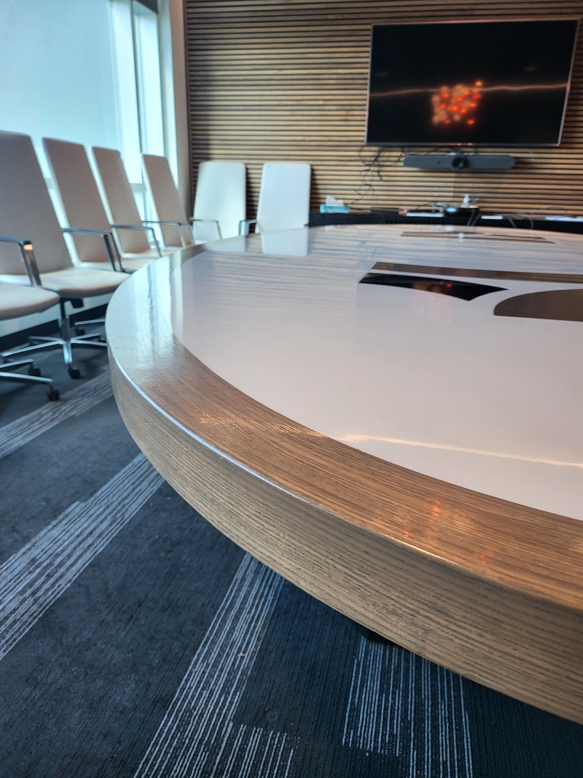 A conference room with a round table and chairs and a flat screen tv