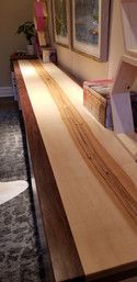 A long wooden table is sitting in a living room next to a rug.