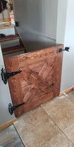 A wooden door is sitting on a tiled floor next to a staircase.