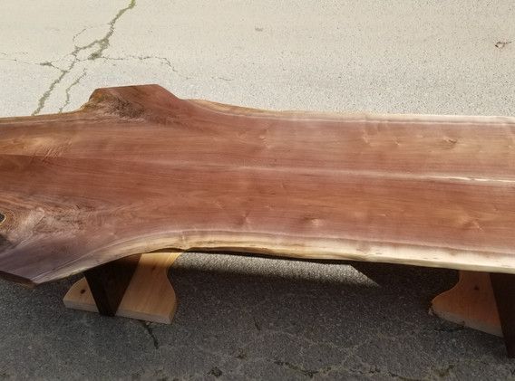 A large piece of wood is sitting on top of a wooden bench.