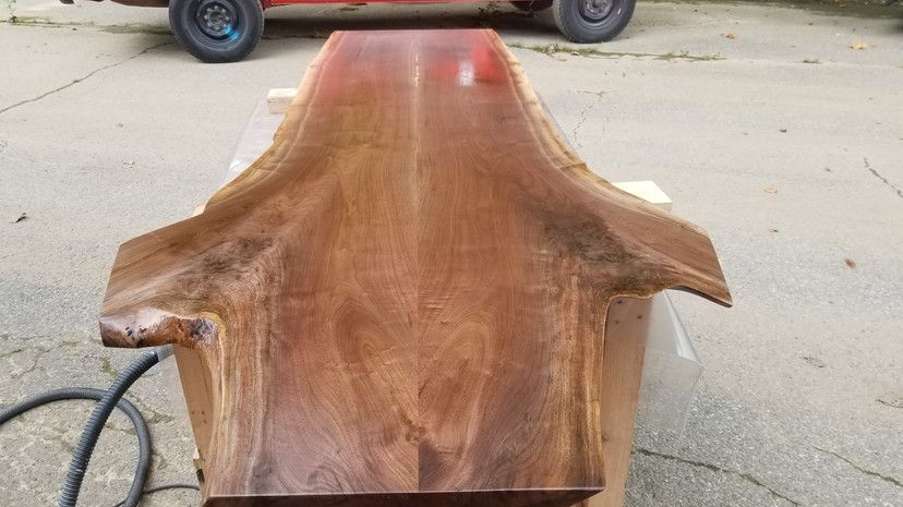 A large piece of wood is sitting on the ground next to a car.