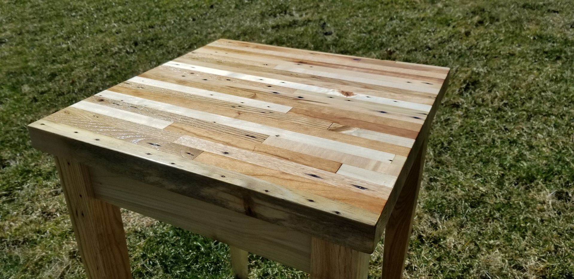 A wooden table is sitting on top of a lush green field.
