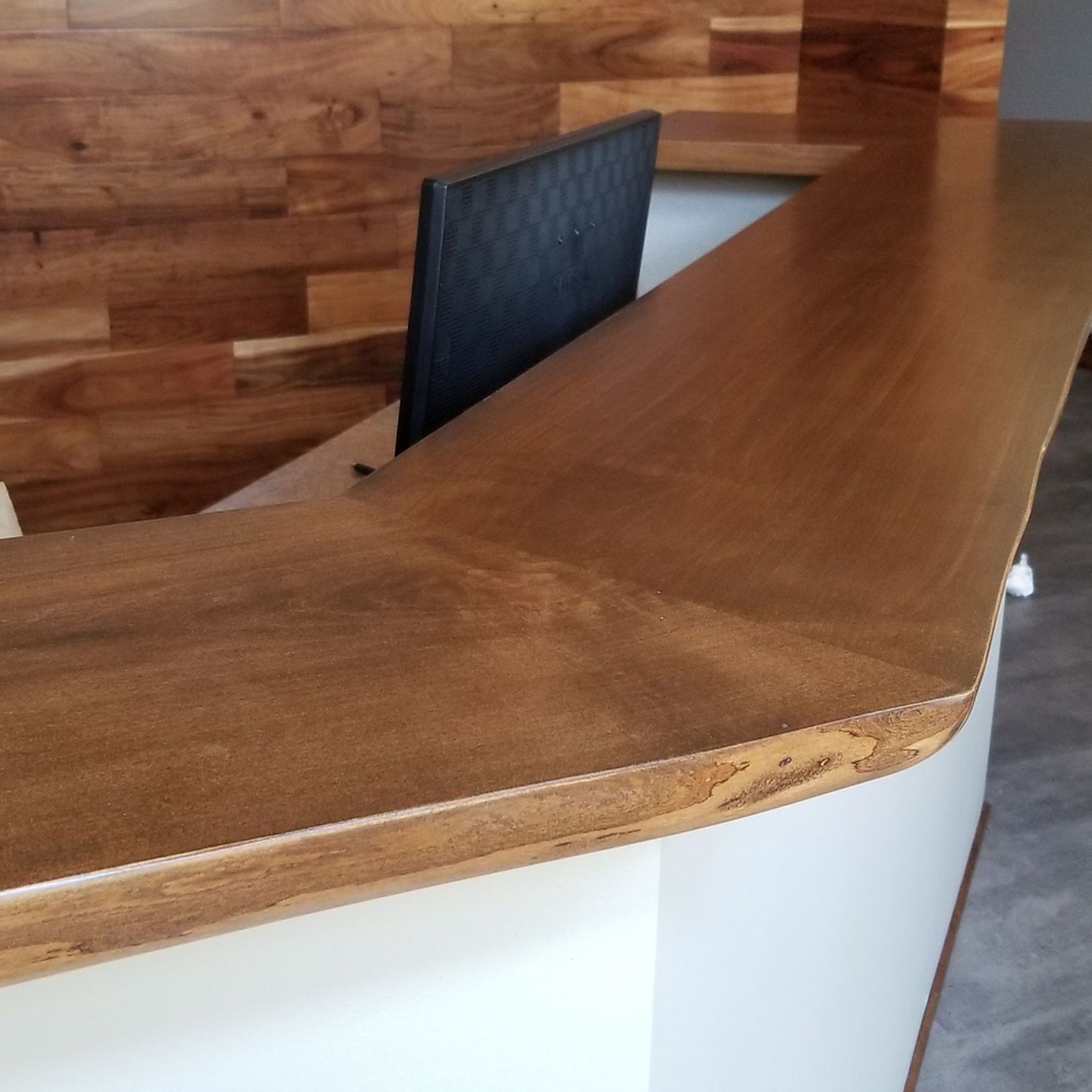 A wooden counter with a black chair behind it