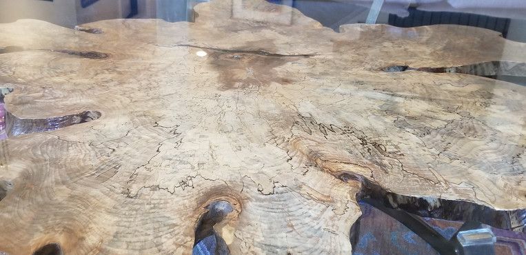 A piece of wood is sitting on top of a glass table.