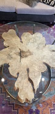 A glass coffee table with a piece of wood on top of it in a living room.
