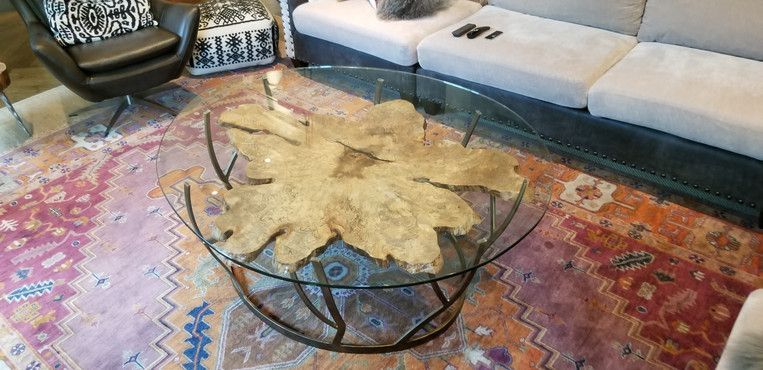 A glass coffee table is sitting on top of a rug in a living room next to a couch.