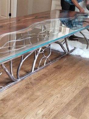 A glass coffee table with a metal frame is sitting on a wooden floor.