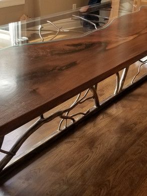 A wooden table with a glass top is sitting on a wooden floor.