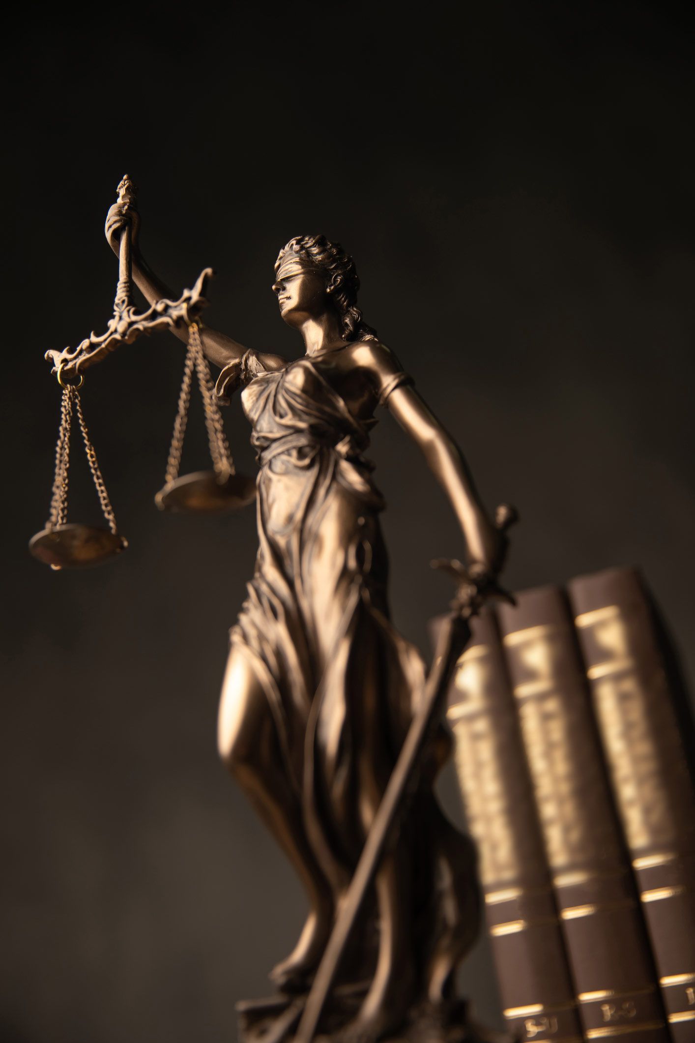 Justice Goddess Statue With Law Books In The Back, Against Grey Studio Background — New Braunfels, Texas — Ronald D. Zipp Attorney At Law
