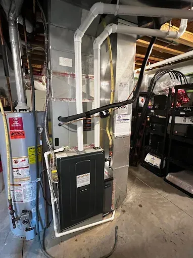 Furnace and water heater in a basement. Metal ducts and pipes are visible.