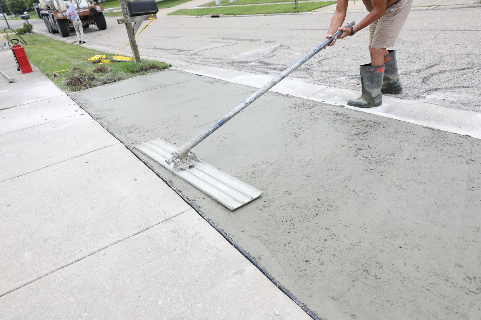 Concreter finishing a new driveway slab with a bull float