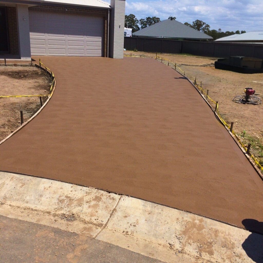 Freshly paved brown driveway leading to a garage on a suburban property