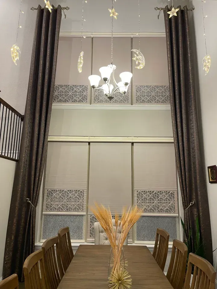 A large window covered with laser cut shades and drapes