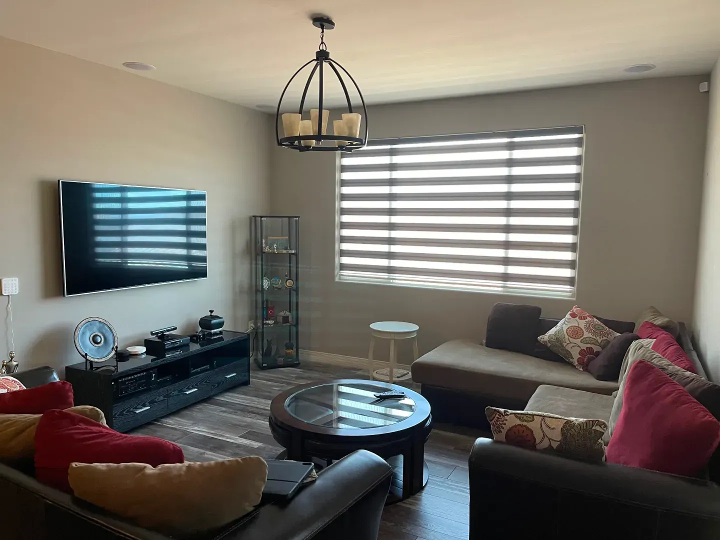 A living room filled with furniture and a flat screen tv and zebra blinds covering the windows