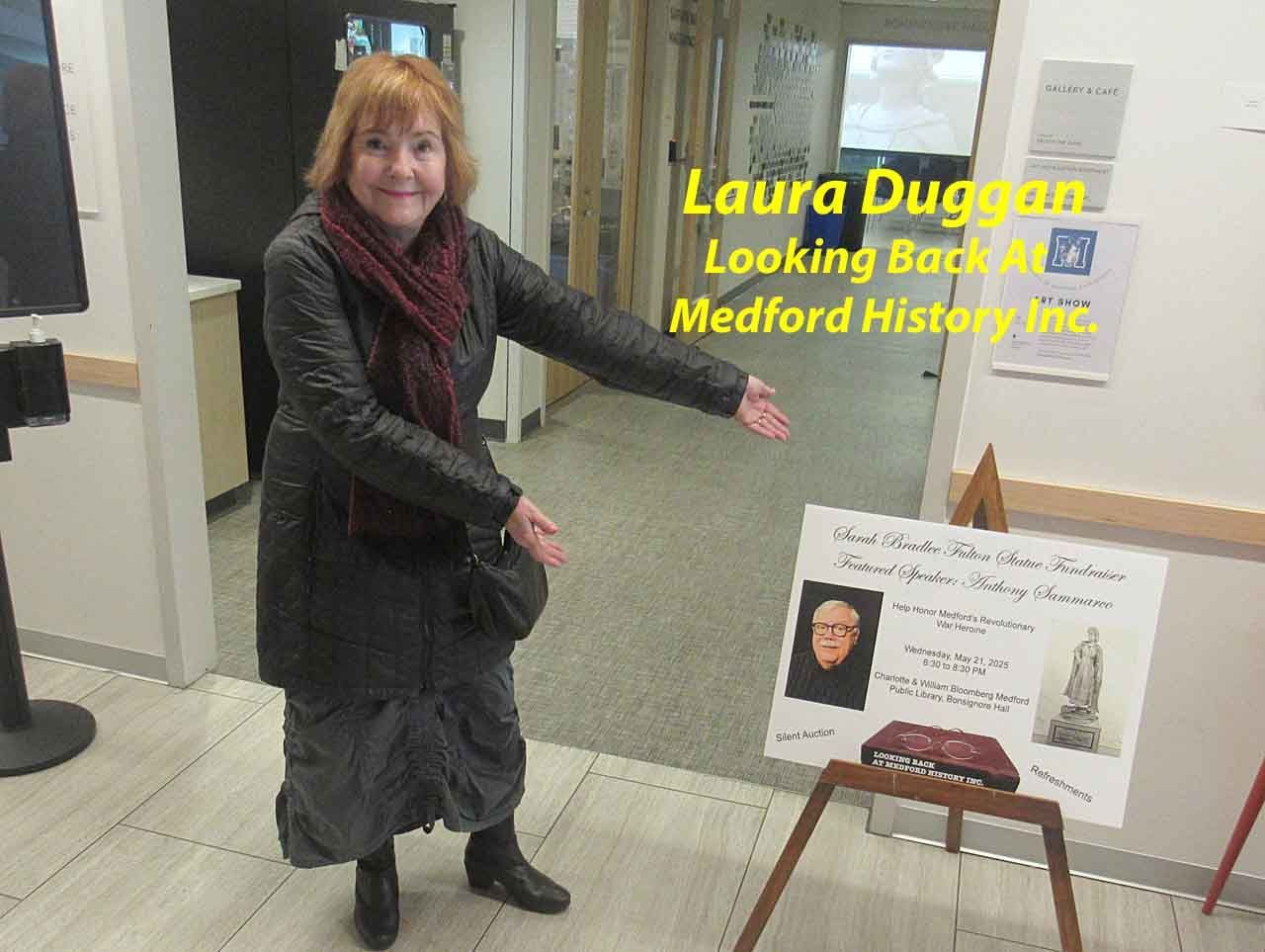 Woman points to a display at Medford History Inc. in a hallway.