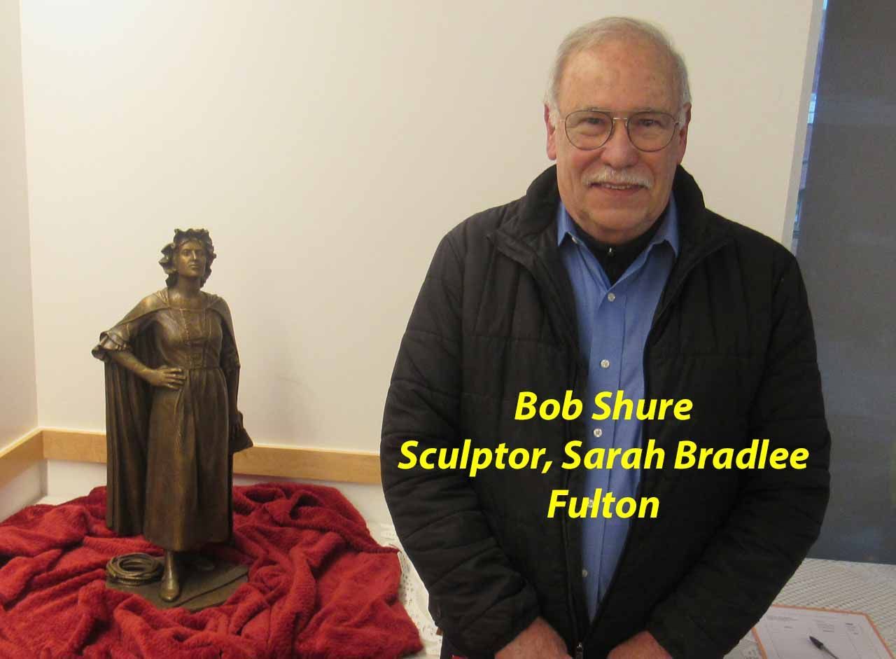 Man stands by a bronze statue of a woman; Bob Shure, sculptor.