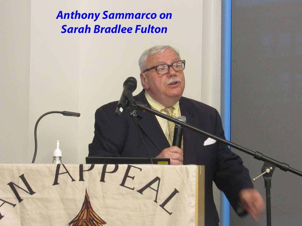 Anthony Sammarco speaking at a podium. Text on banner reads 
