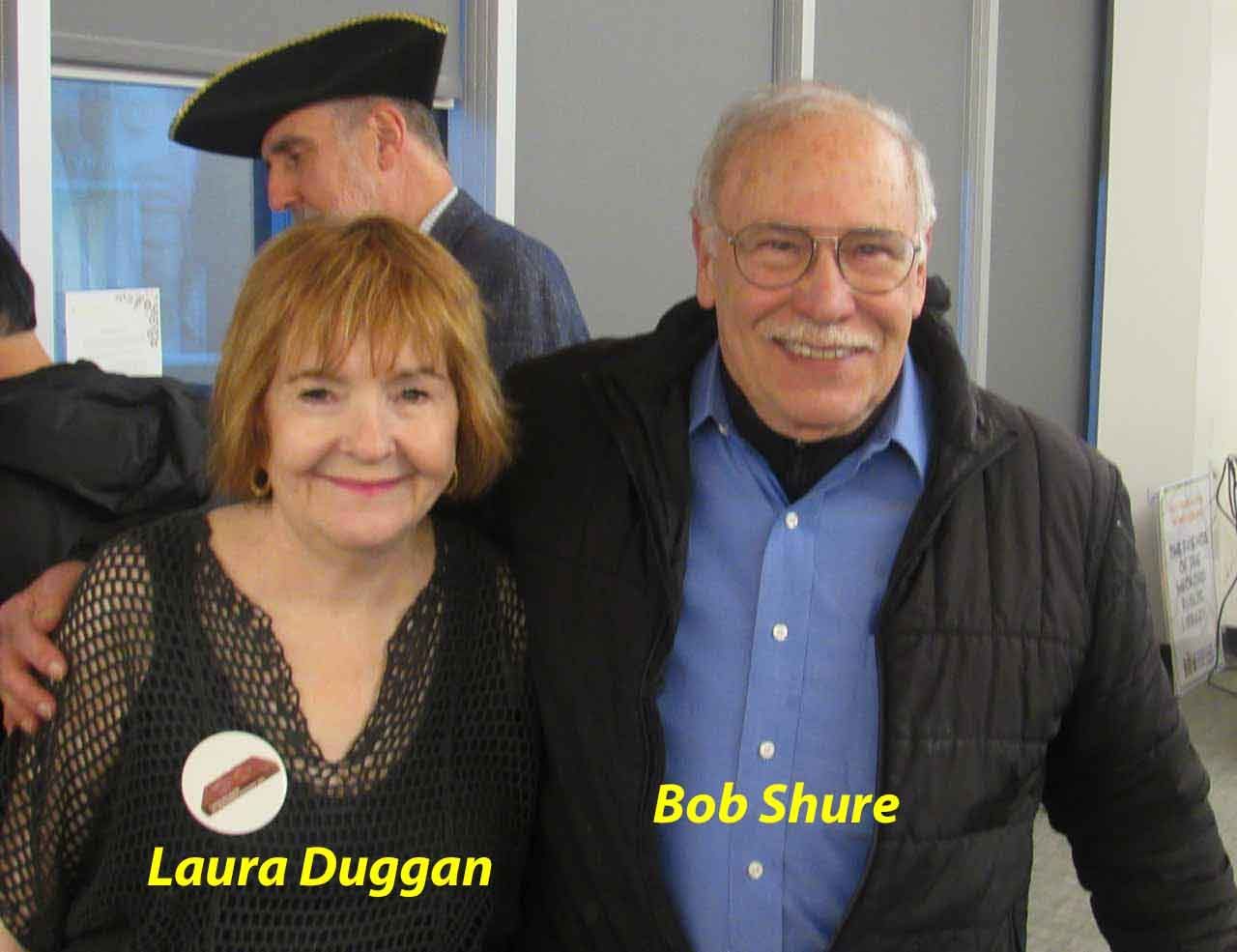 Laura Duggan and Bob Shure smiling for the camera. A man in a tricorn hat in the background.