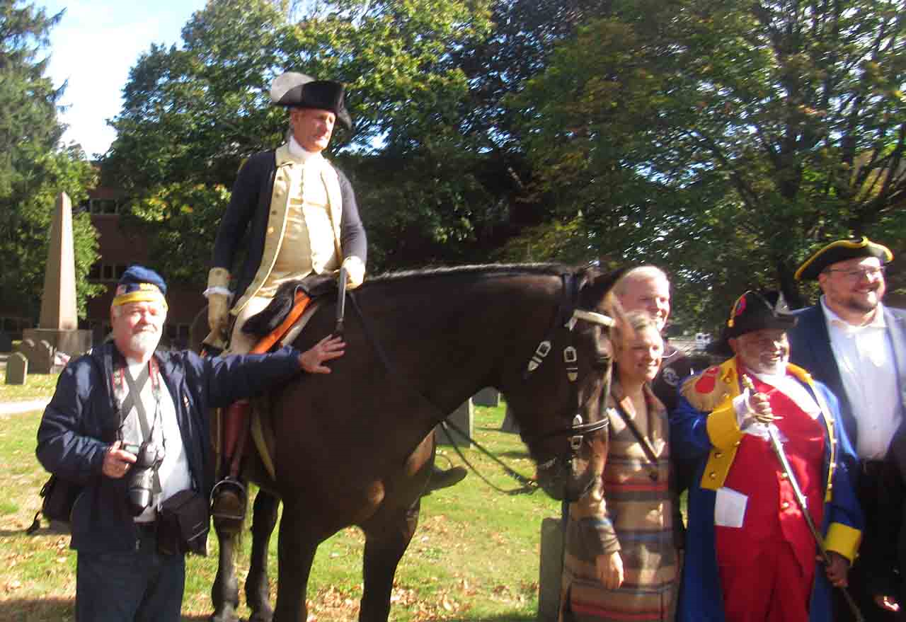 A man riding a horse with a group of people standing behind him