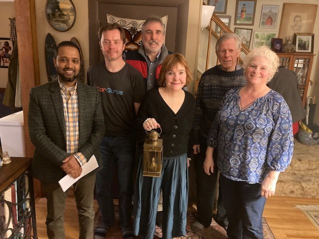 A group of people standing in a living room with a woman holding a lantern