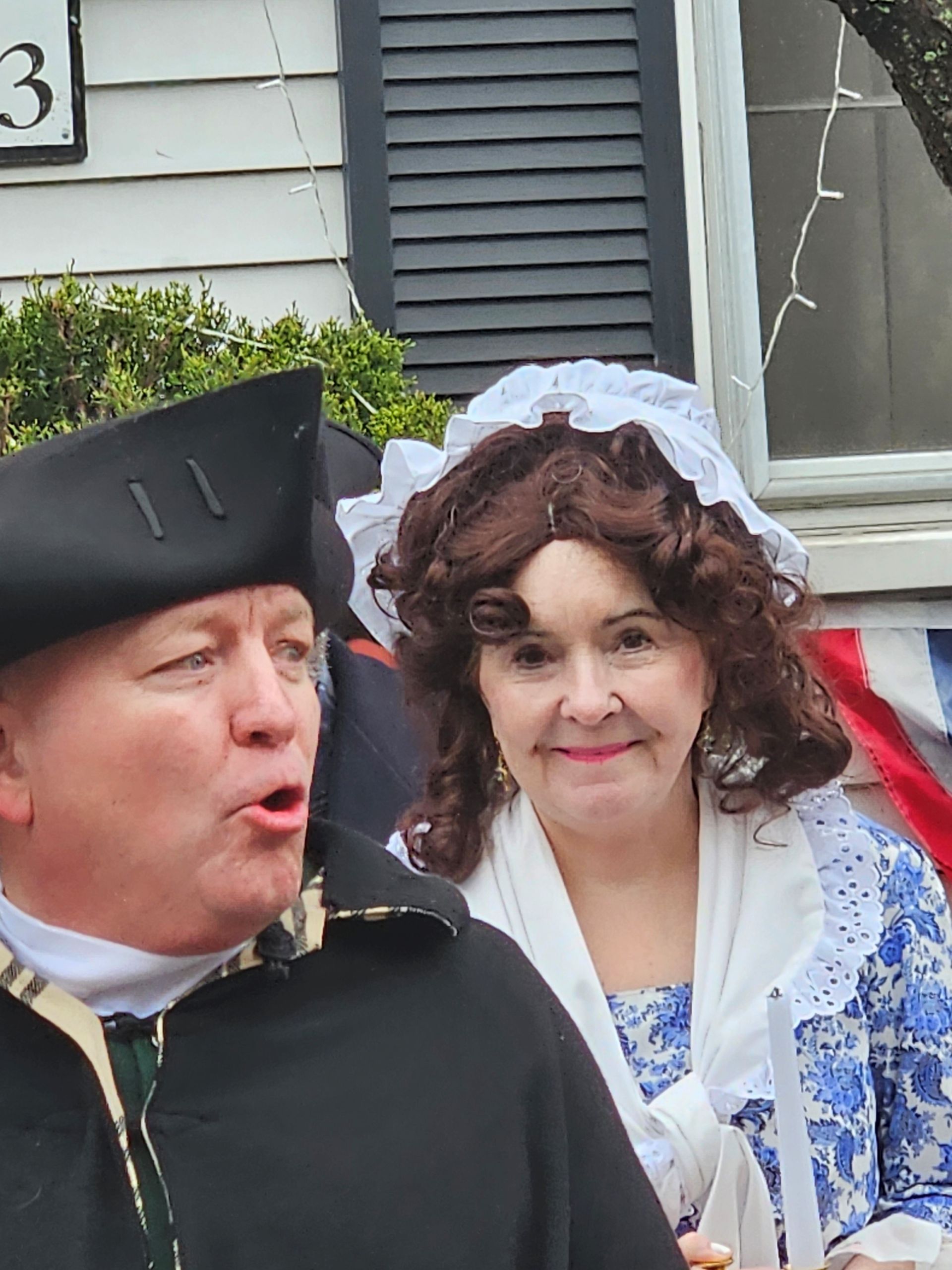 A man and a woman are standing in front of a house numbered 3