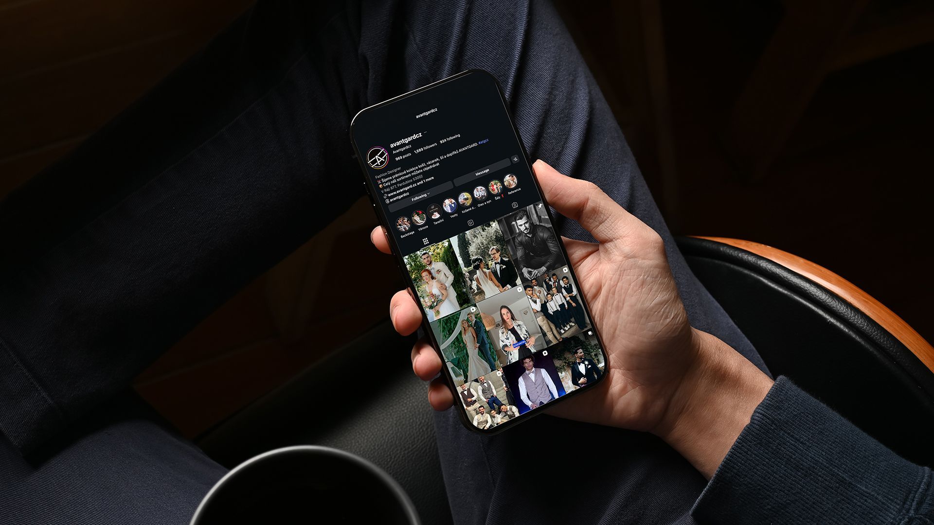 Ruka držící smartphone zobrazující kanál sociálních médií v tmavém prostředí