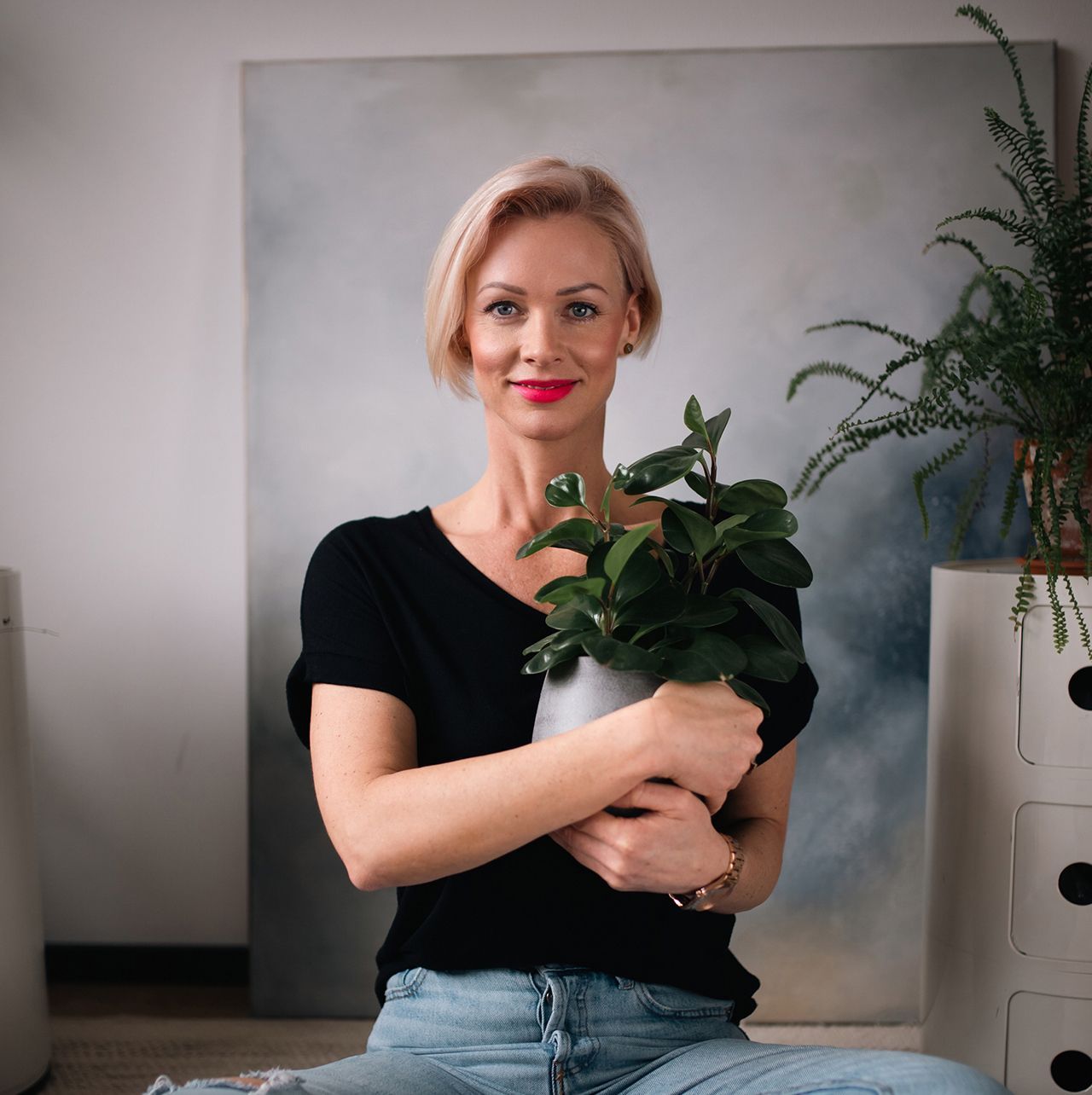 Žena v černé košili držící květinu v prosvětlené místnosti