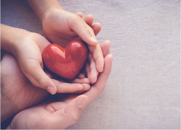 Hands gently holding a red heart-shaped object