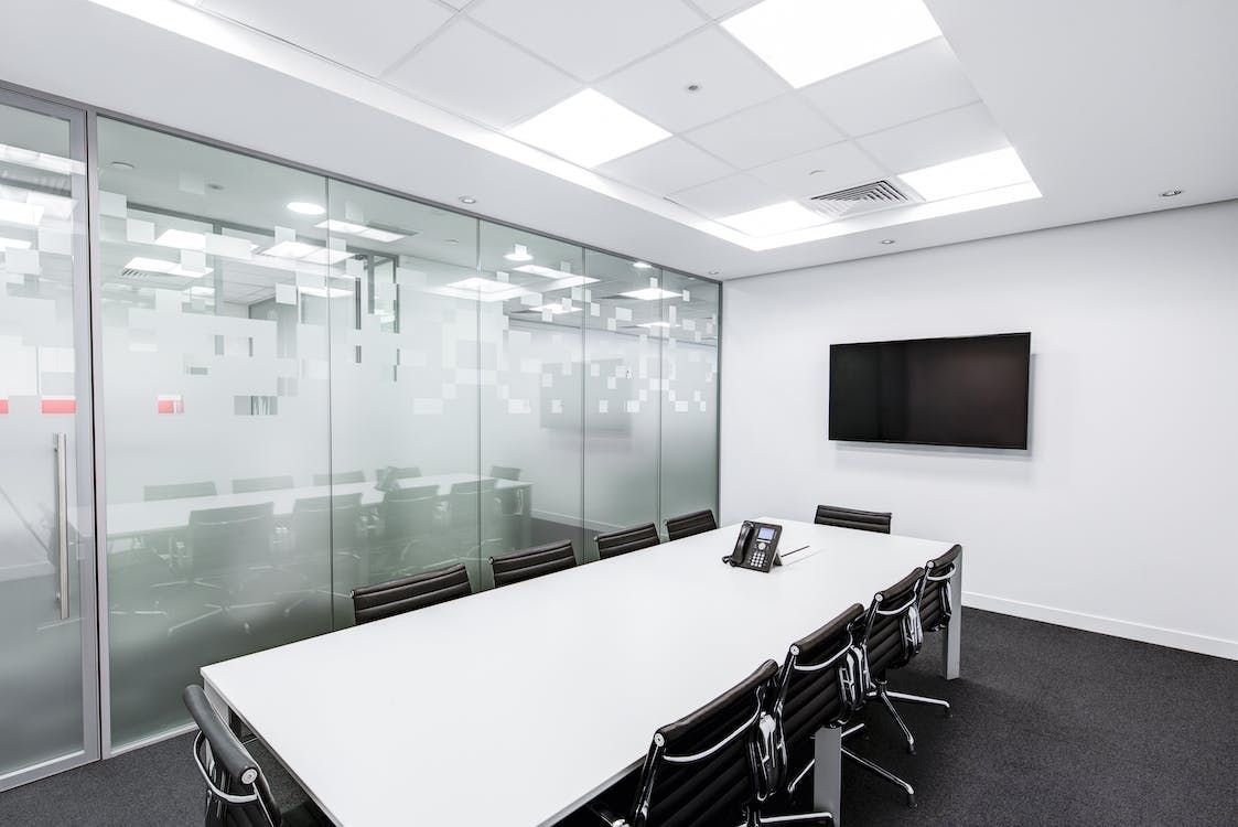 A conference room with a long table and chairs and a flat screen tv on the wall.