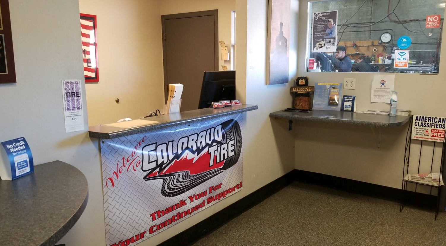 Reception desk with TV station banner and side counter in an office lobby | Colorado Tire Auto Care Center