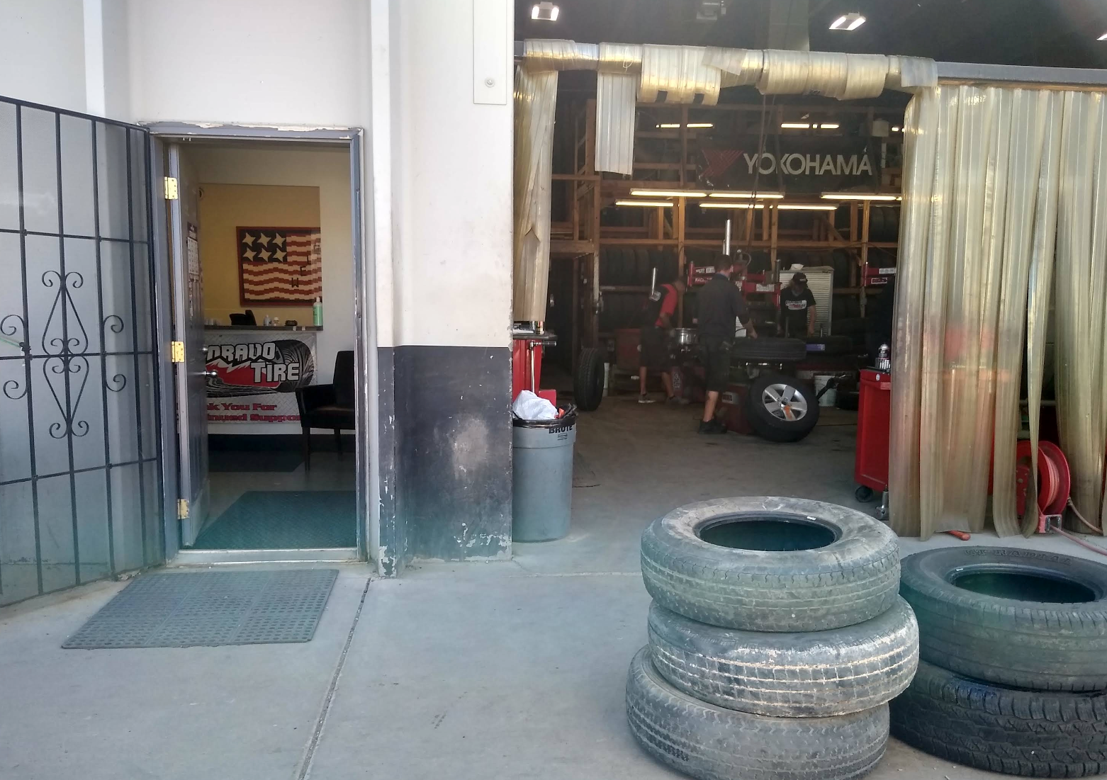 Auto shop entrance with stacked tires in front and a car inside behind a curtain | Colorado Tire Auto Care Center
