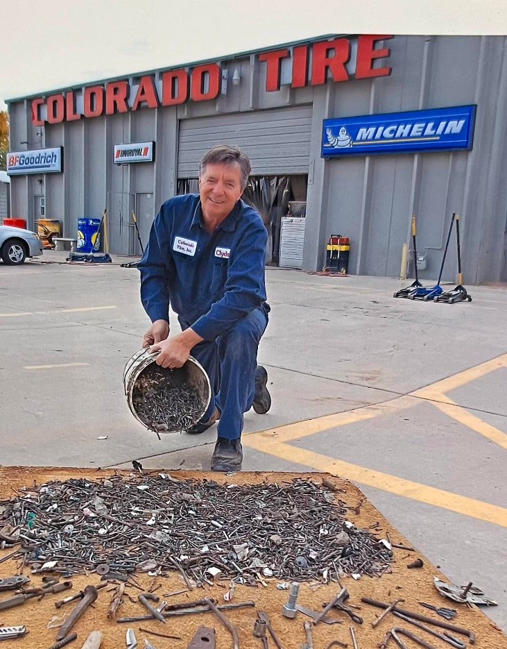 Mechanic pours debris from a tire onto the pavement outside Colorado Tire shop. | Colorado Tire Auto Care Center