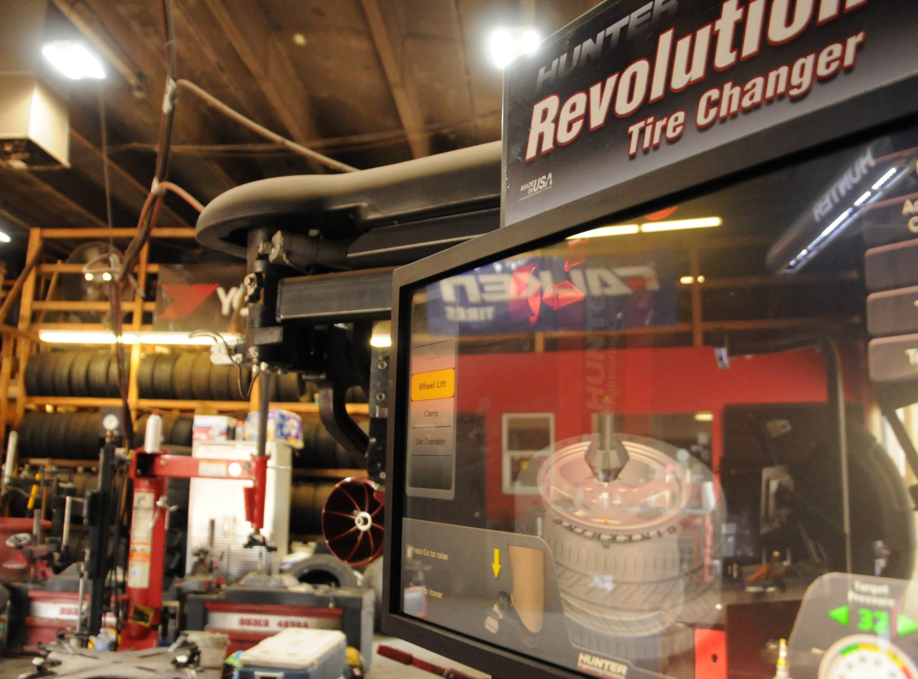 Revolution tire changer machine in an industrial workshop with hoses and equipment. | Colorado Tire Auto Care Center
