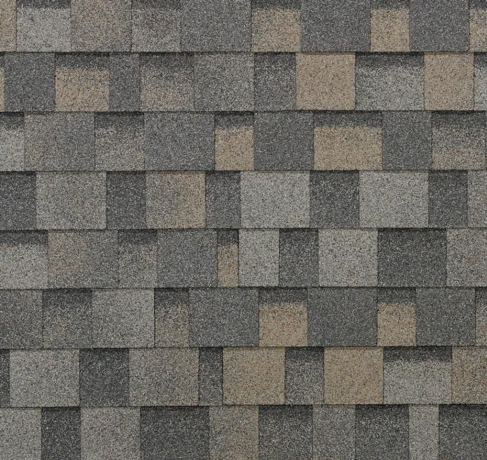 Bardeaux de toiture en asphalte gris et beige, posés en quinconce.