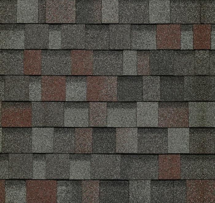 Gros plan sur des bardeaux d'asphalte dans des tons de gris, de brun-rouge et de noir, utilisés comme matériau de toiture.