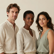 Three people standing together in neutral-toned clothing against a beige background
