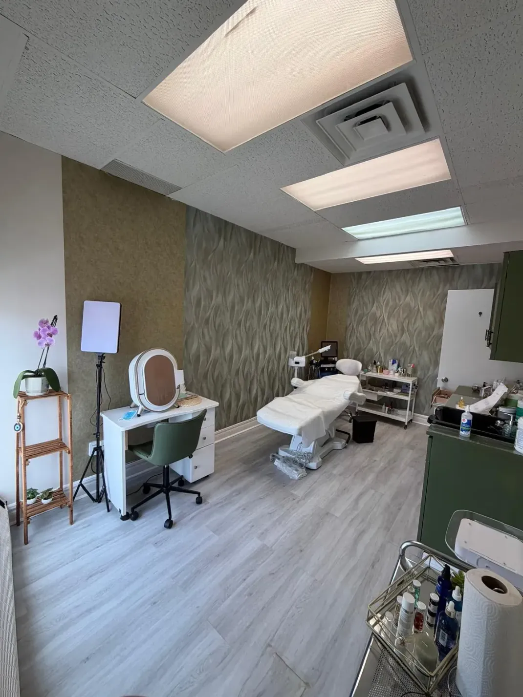 Modern medical treatment room with exam tables, ceiling lights, and equipment, viewed from the doorway