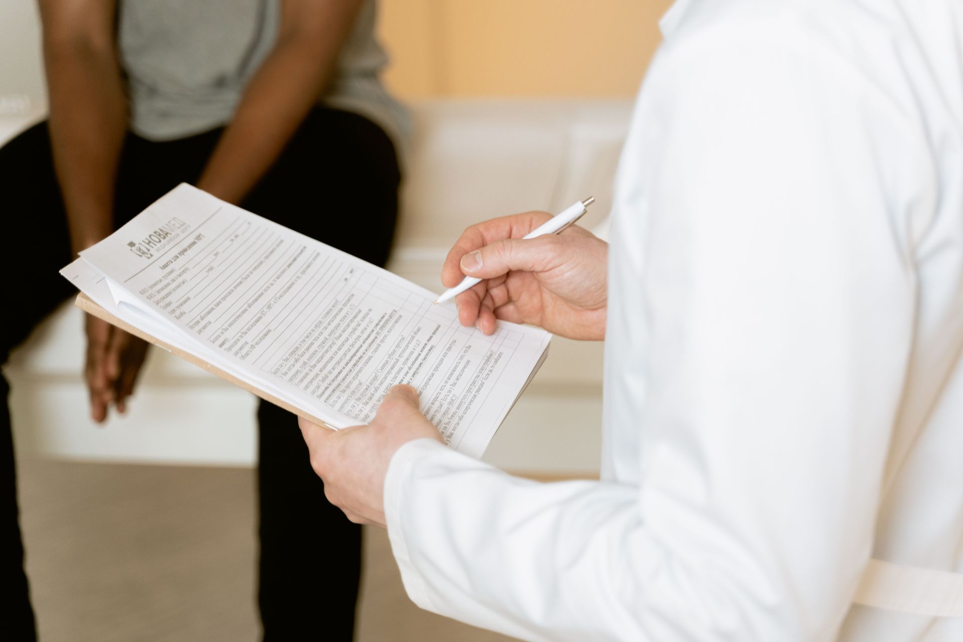 Person writing on a document during an interview or consultation indoors