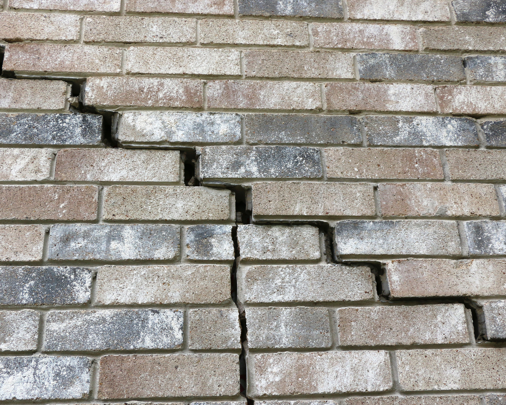 Cracked brick wall, with a prominent vertical crack running down the center.