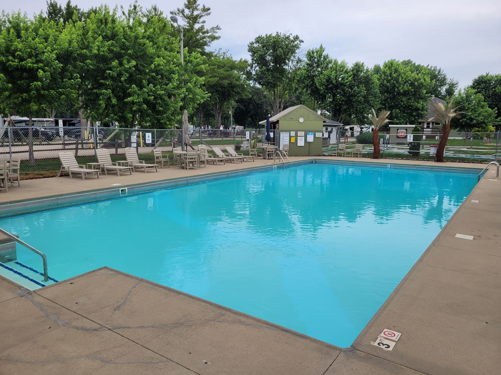 A large swimming pool surrounded by chairs on a sunny day