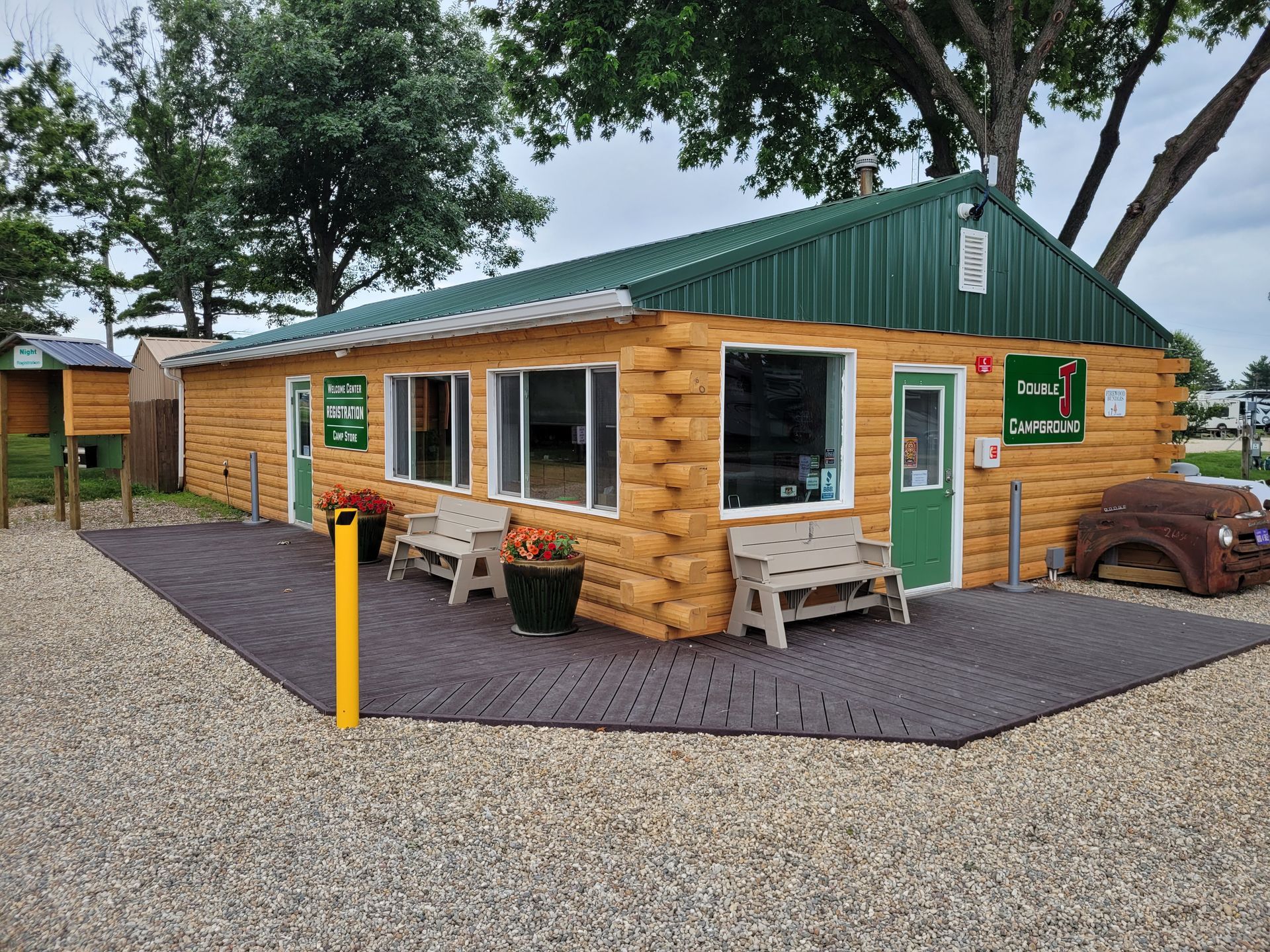 A small wooden building with a green roof and benches in front of it.