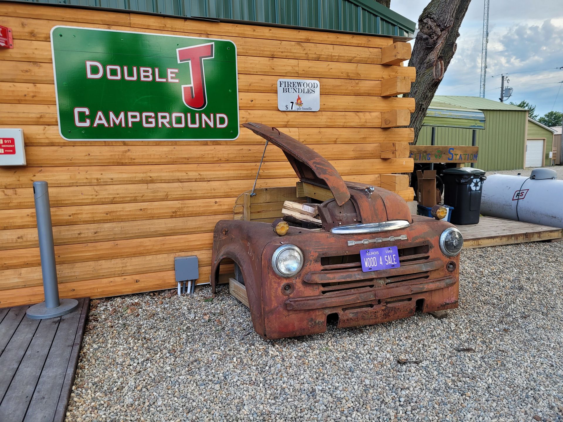 An old rusty truck is parked in front of a wooden building with a sign that says double j campground.