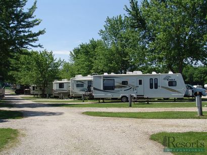 A row of rv 's are parked in a resort 's parking lot