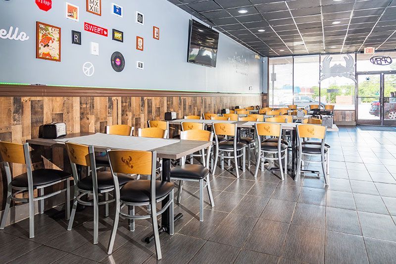 Bright fast-food dining room with empty tables, metal chairs, and wall decor near the entrance.