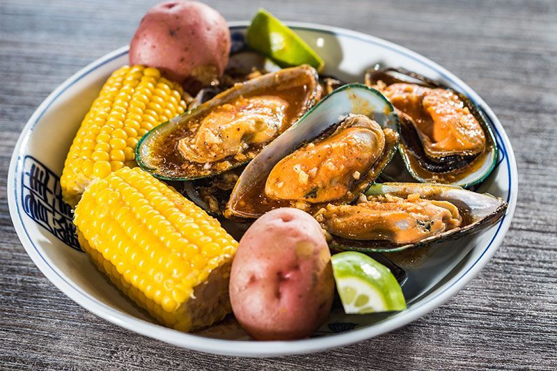 Seafood boil with mussels, corn, red potatoes, and lime wedges on a plate