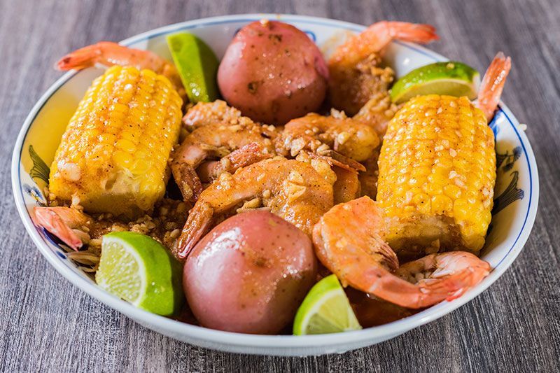 Seafood boil with corn, shrimp, potatoes, sausage, and lime wedges in a bowl