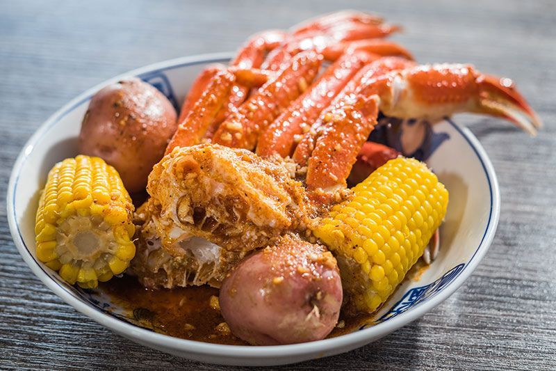 Seafood boil with crab legs, corn on the cob, potatoes, and sauce on a plate